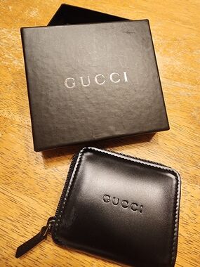 black leather Gucci zip-around coin purse featuring a debossed Gucci logo